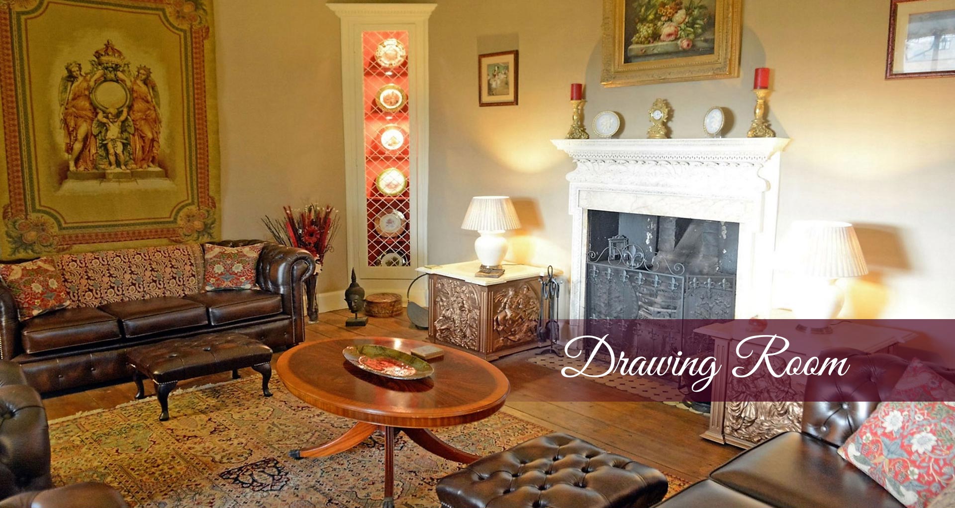 Drawing Room Banner showing leather chesterfields and the original Italian fireplace with antique furnishings and a large tapestry on the far wall - At Plas Tan-Yr-Allt - 5-Star luxury, literary & historic Country House B&B in Tremadog, Porthmadog, Snowdonia.